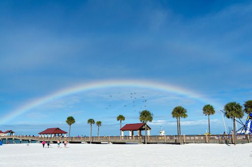 Clearwater beach with a rainbow and birds flying through the sky