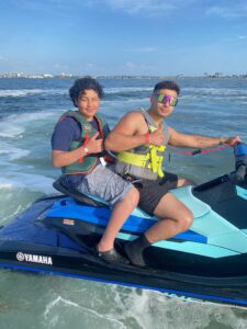 Two boys on a jet ski, using appropriate safety gear